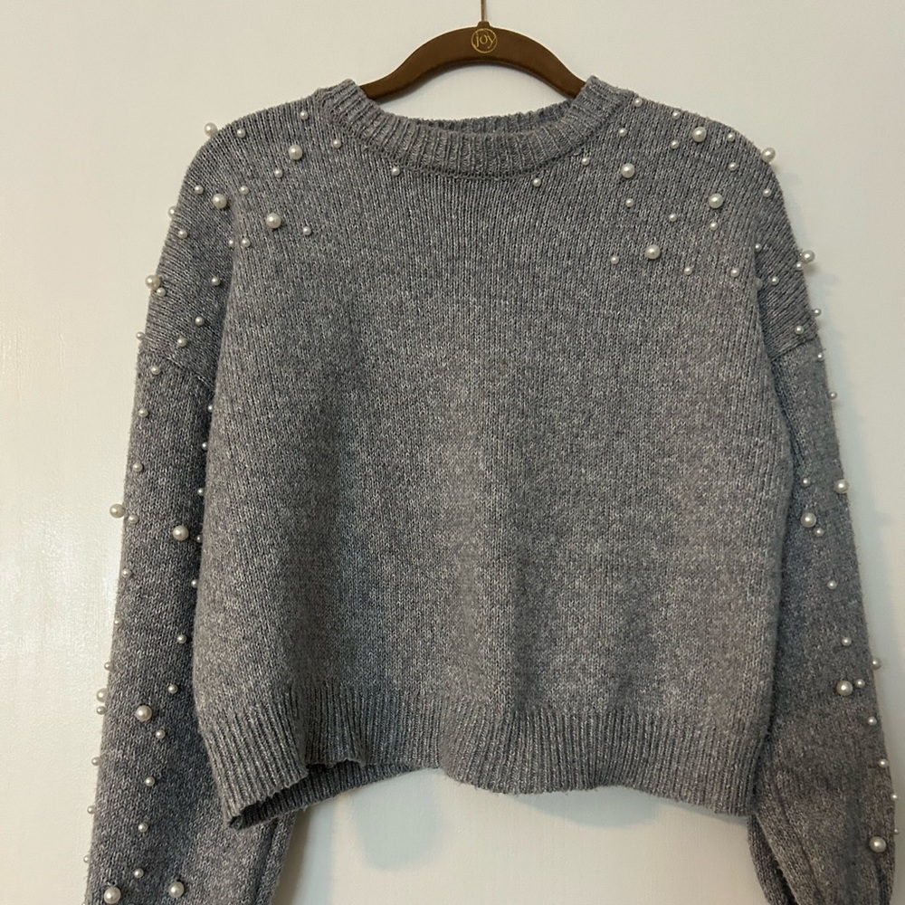 Gray sweater with pearls along the arms.